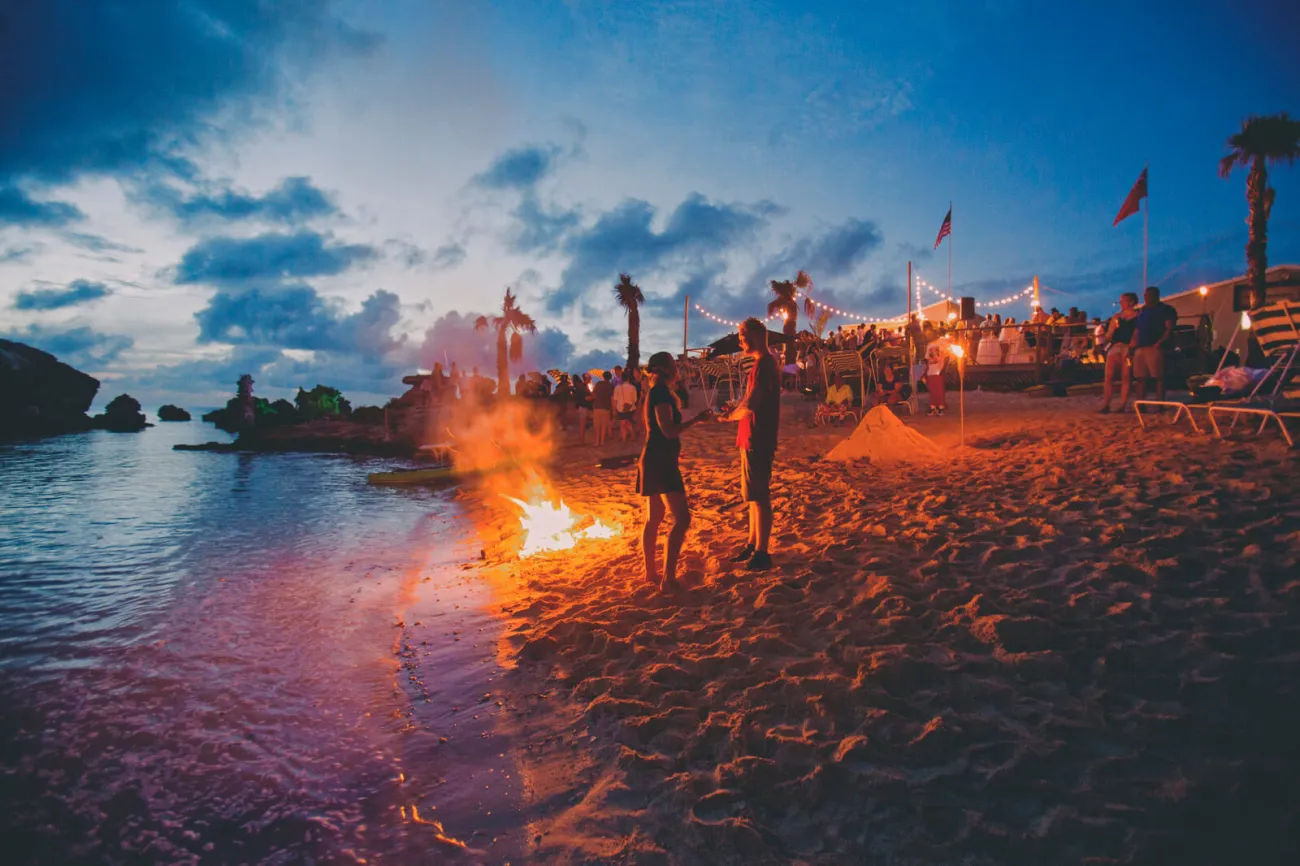 People standing on the beach next to a bonfire at Tobacco Bay