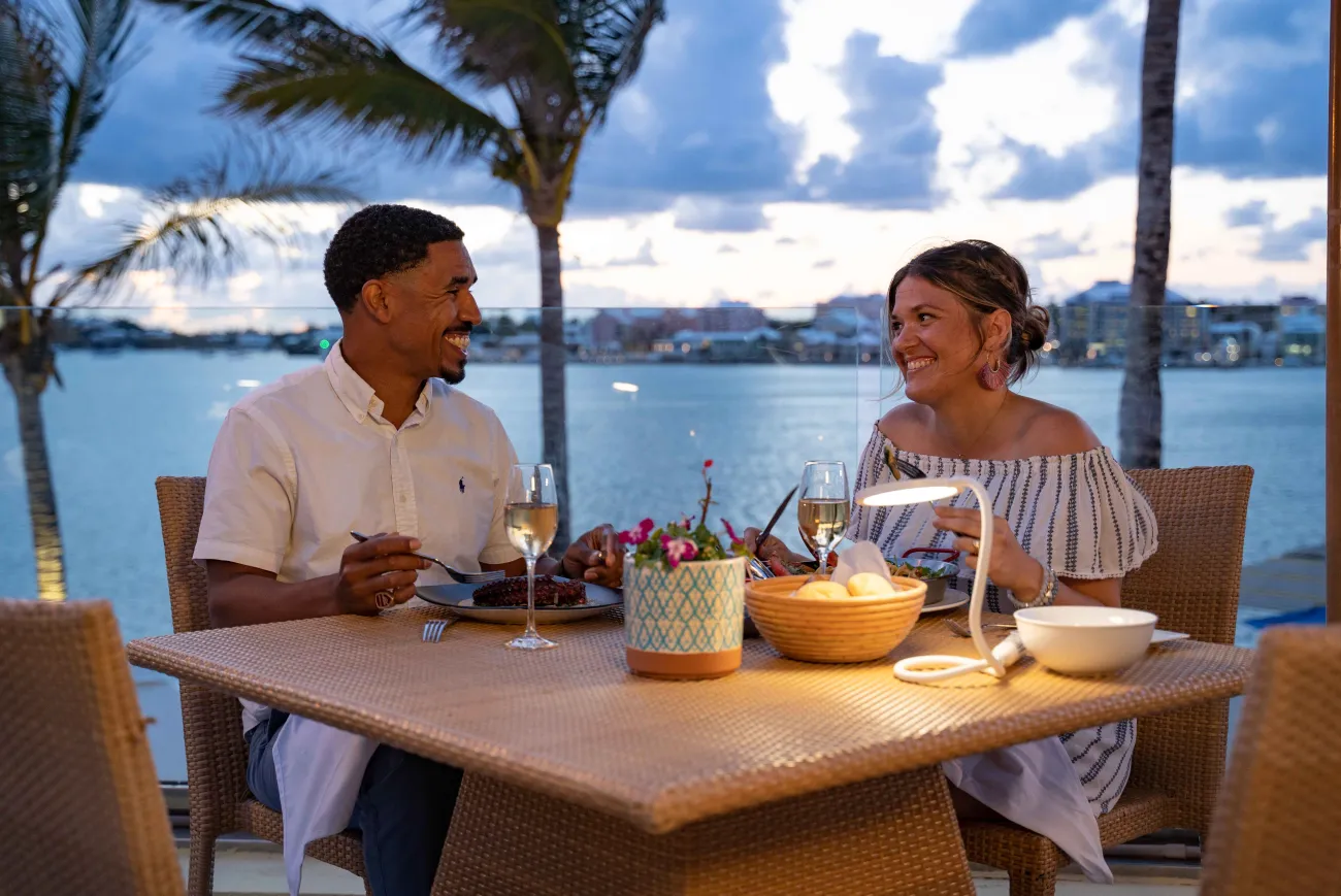 A couple is sitting at a dining table with a scenic background.