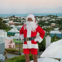 A man dressed as Santa is standing on a Bermuda house roof.